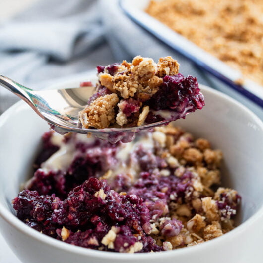 healthy berry crumble on a spoon above a bowl