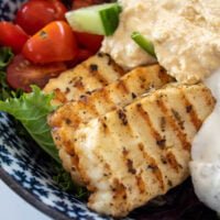 marinated fried halloumi in a salad bowl with hummus and yoghurt dip