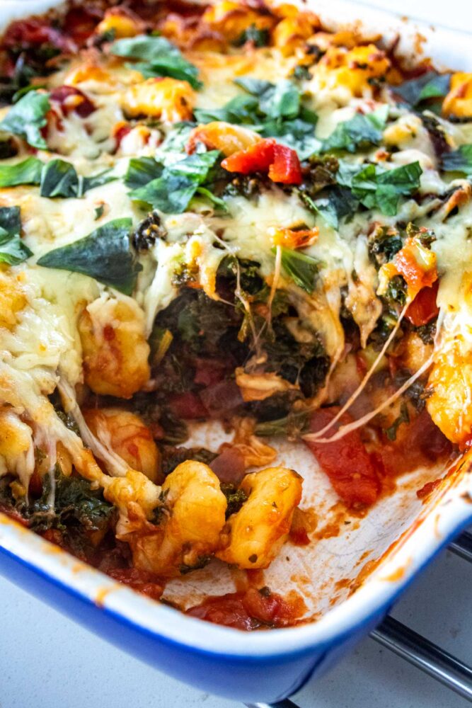 crispy kale gnocchi bake with a serving taken out of the dish