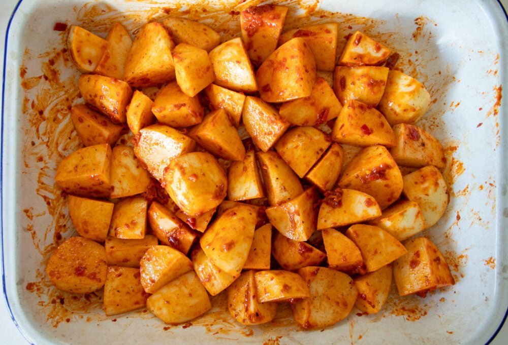 uncooked harissa potatoes in a roasting tray