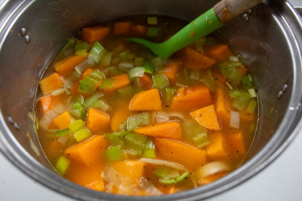 butternut squash and chopped leeks with vegetable stock in a saucepan