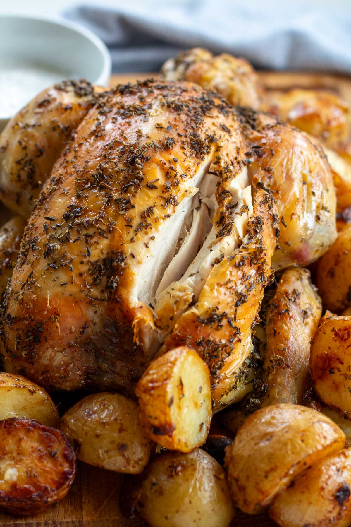 closeup of Greek Roast Chicken surrounded by Garlic Roasted Potatoes on a board