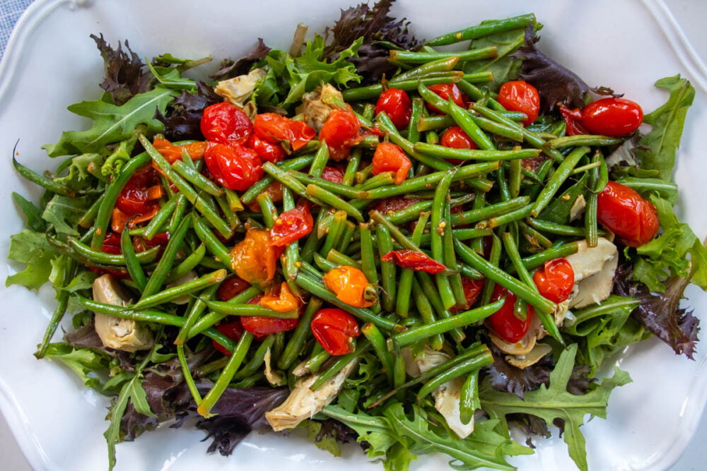roasted green beans and tomatoes on salad leaves