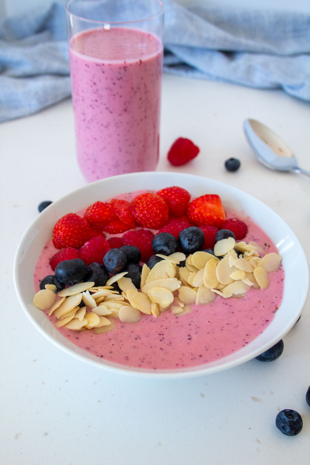 berry smoothie bowl with a glass of berry smoothie no banana in the background