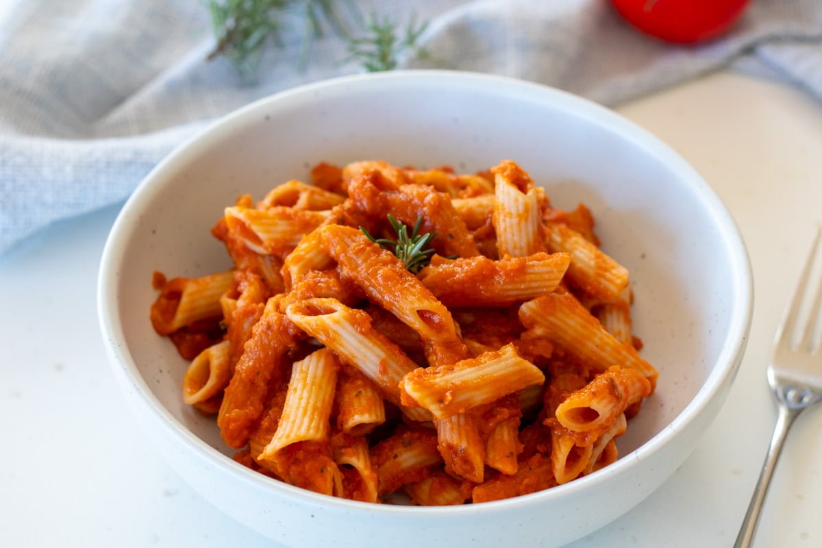 Butternut Squash Pasta Sauce mixed into penne pasta in a bowl