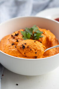 paprika hummus in a bowl with a spoon