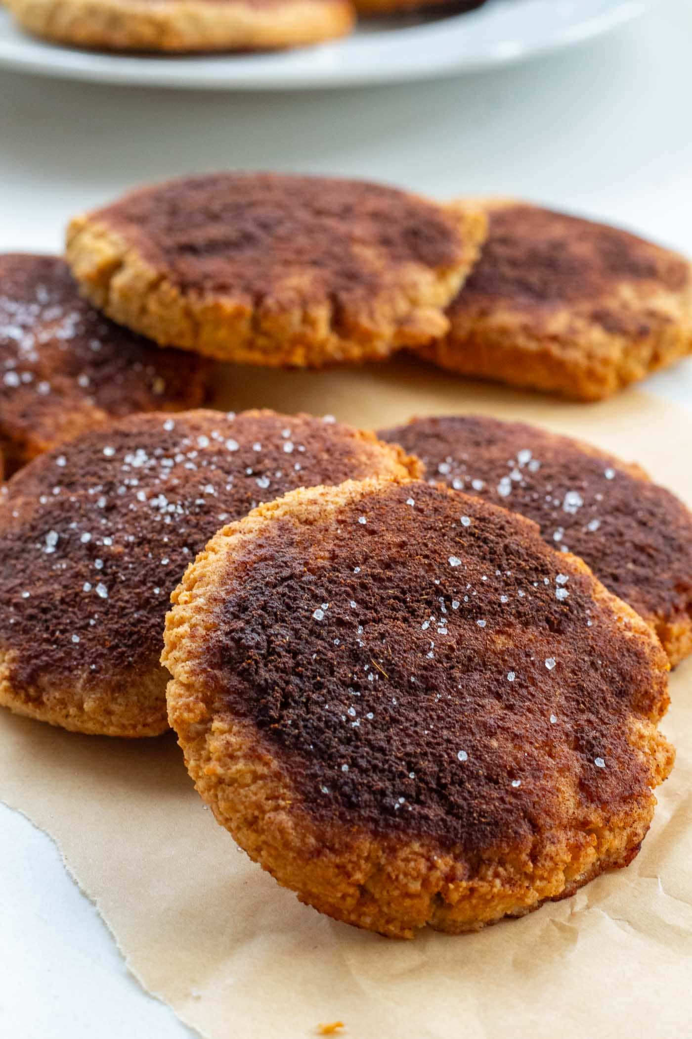 A pile of freshly baked gluten-free cinnamon cookies with more cookies visible in the background.