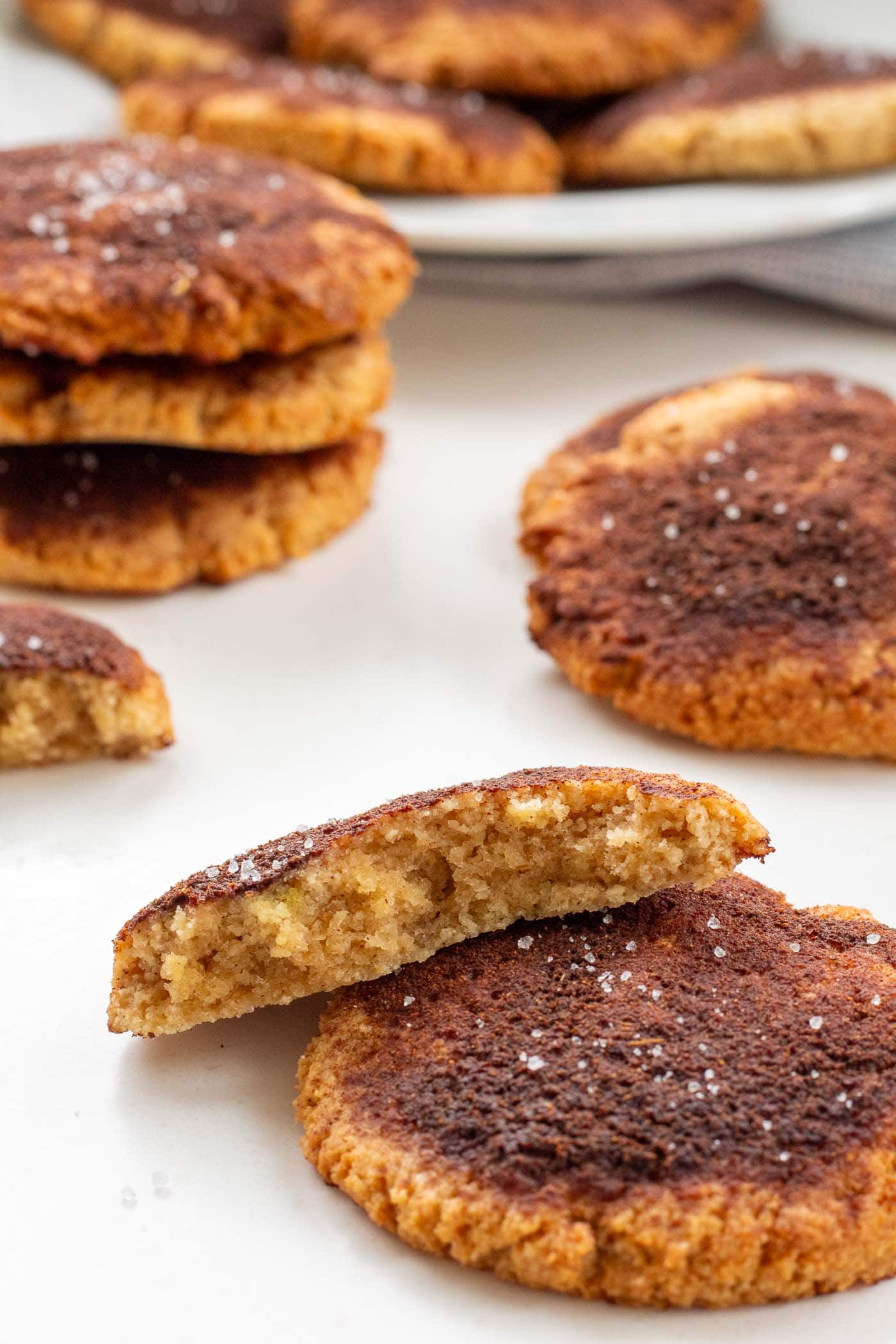 Diabetic-friendly cinnamon cookie broken in half revealing the soft interior texture, resting on another cookie with more in the background
