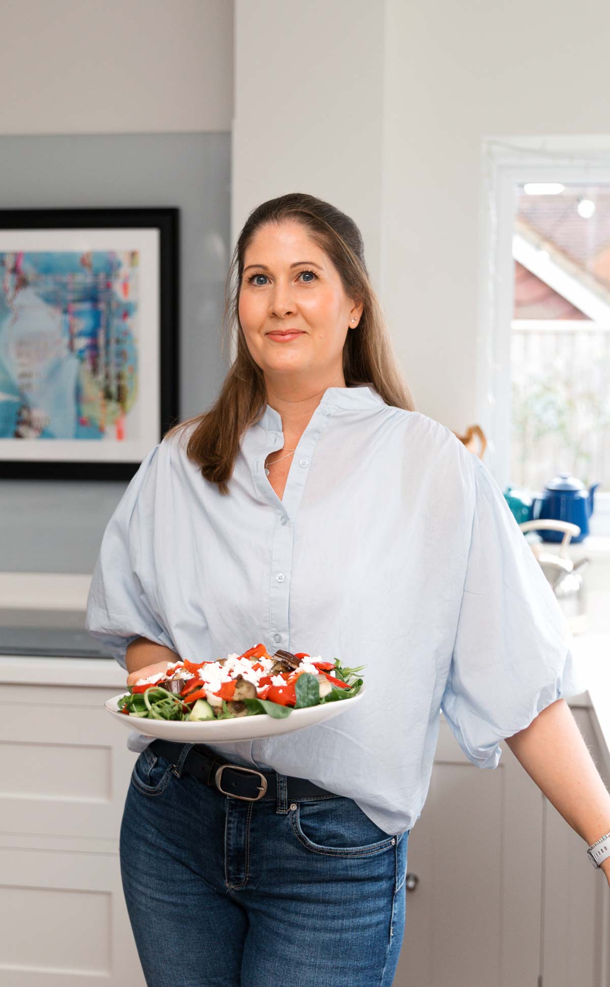 Michelle Rorke, founder of Whole Hearty Kitchen, holding a plate of food and smiling in her kitchen - diabetes food blogger UK
