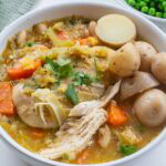 Chicken and leek casserole with shredded chicken, carrots, beans and baby potatoes served with green vegetables